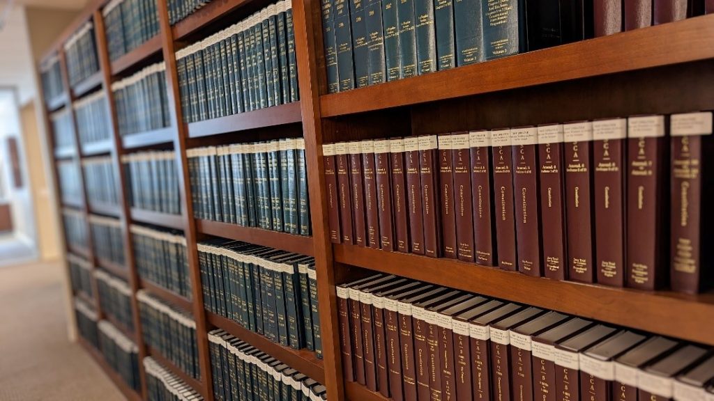 Wooden book cases holding a variety of green and red legal texts.